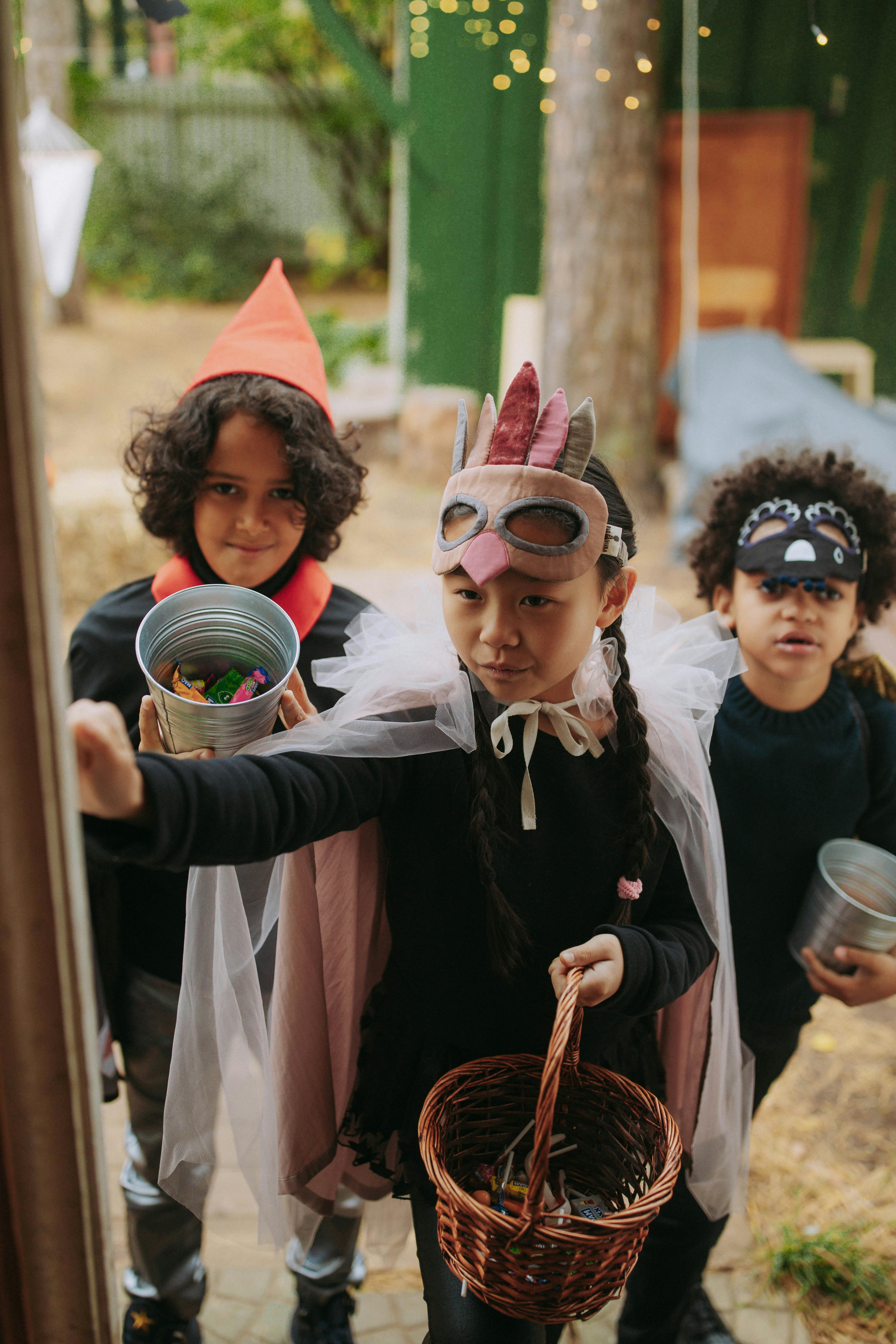 Three children in Halloween outfits trick or treating at a decorated door